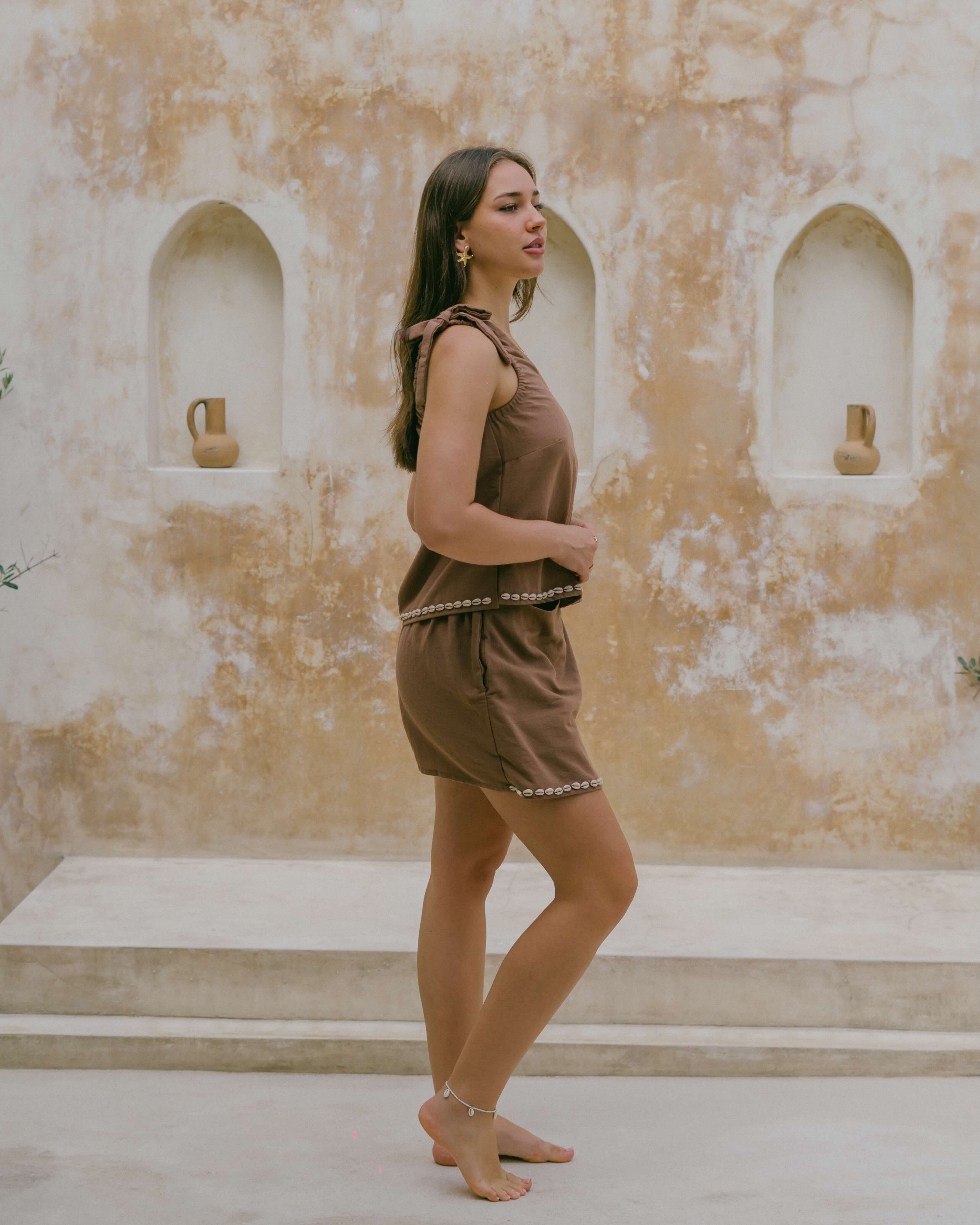 Designed for balmy days, the Coralie Shell Top is lightweight, relaxed, and finished with cowrie shells for a touch of seaside charm.