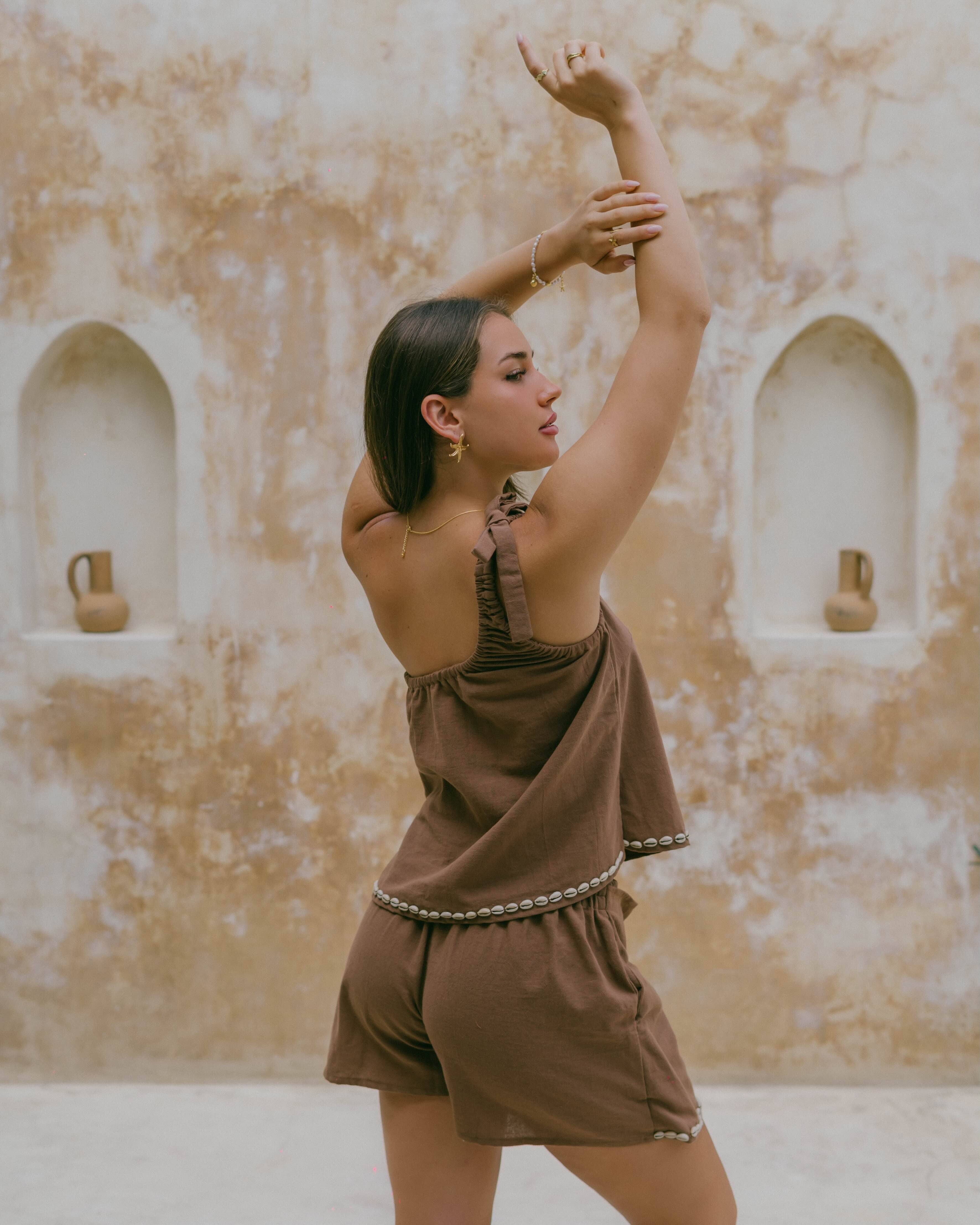 A versatile piece, the Coralie Shell Top pairs perfectly with matching bottoms or denim, featuring a flowy silhouette and coastal-inspired accents.