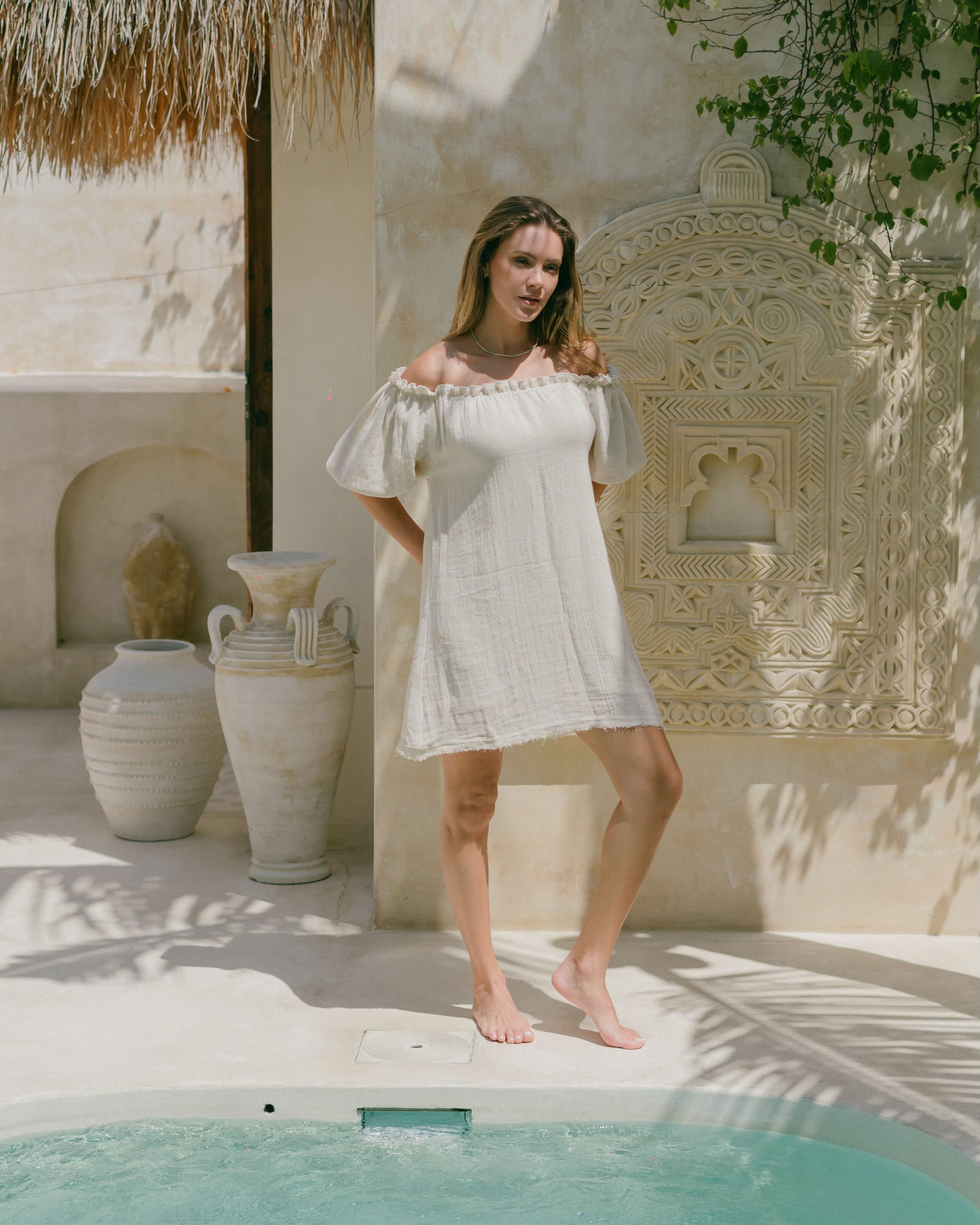 A chic summer mini dress in 100% ramie with puff sleeves, ruffled neckline, and frayed hemline. Breathable, comfy, and timeless for warm-weather outfits.