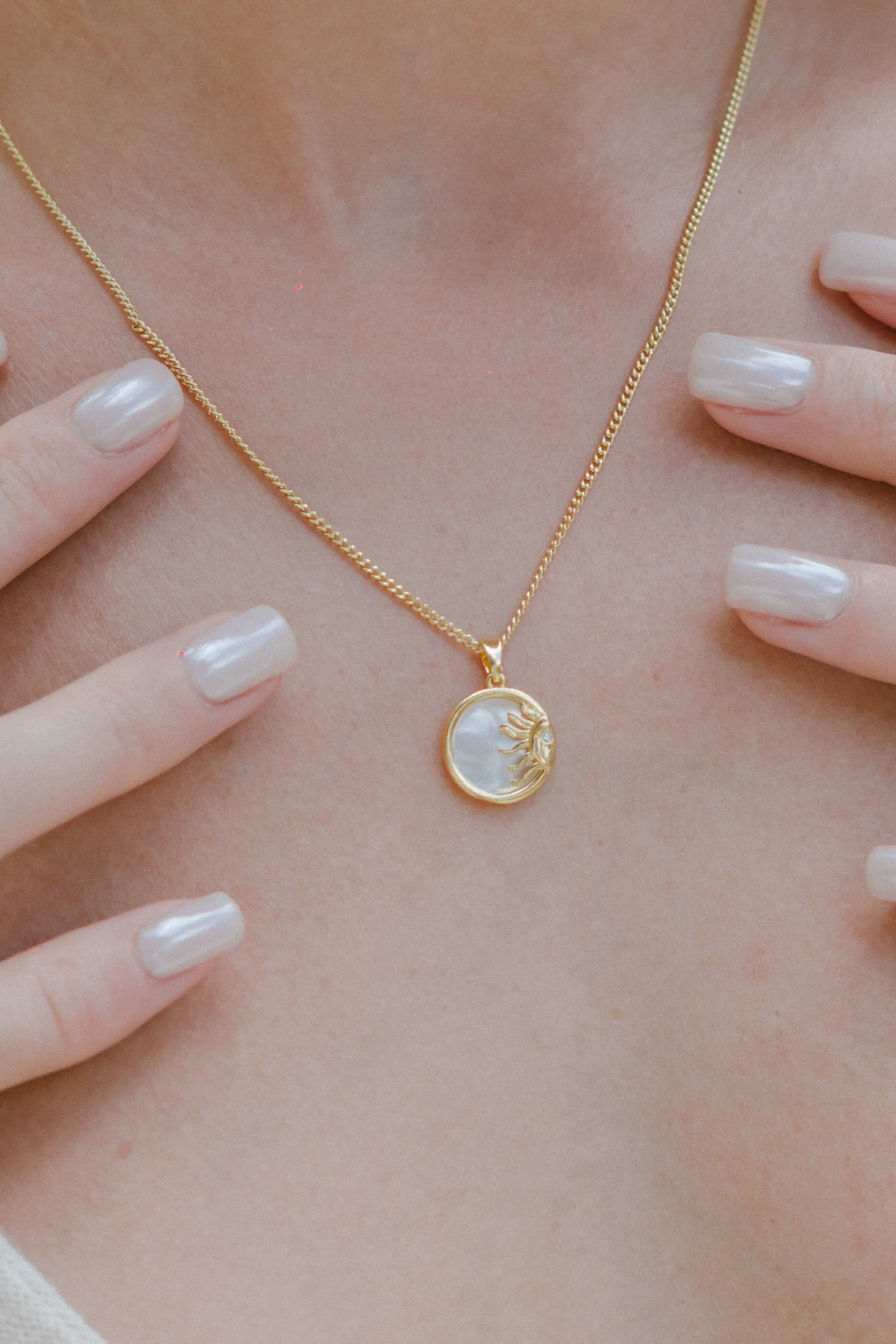 Shop the Sunstone Pearl Pendant Necklace—an 18k gold chain featuring a round pearl pendant with gold sun rays and a sleek gold outline. Perfect for layering or standout everyday wear.