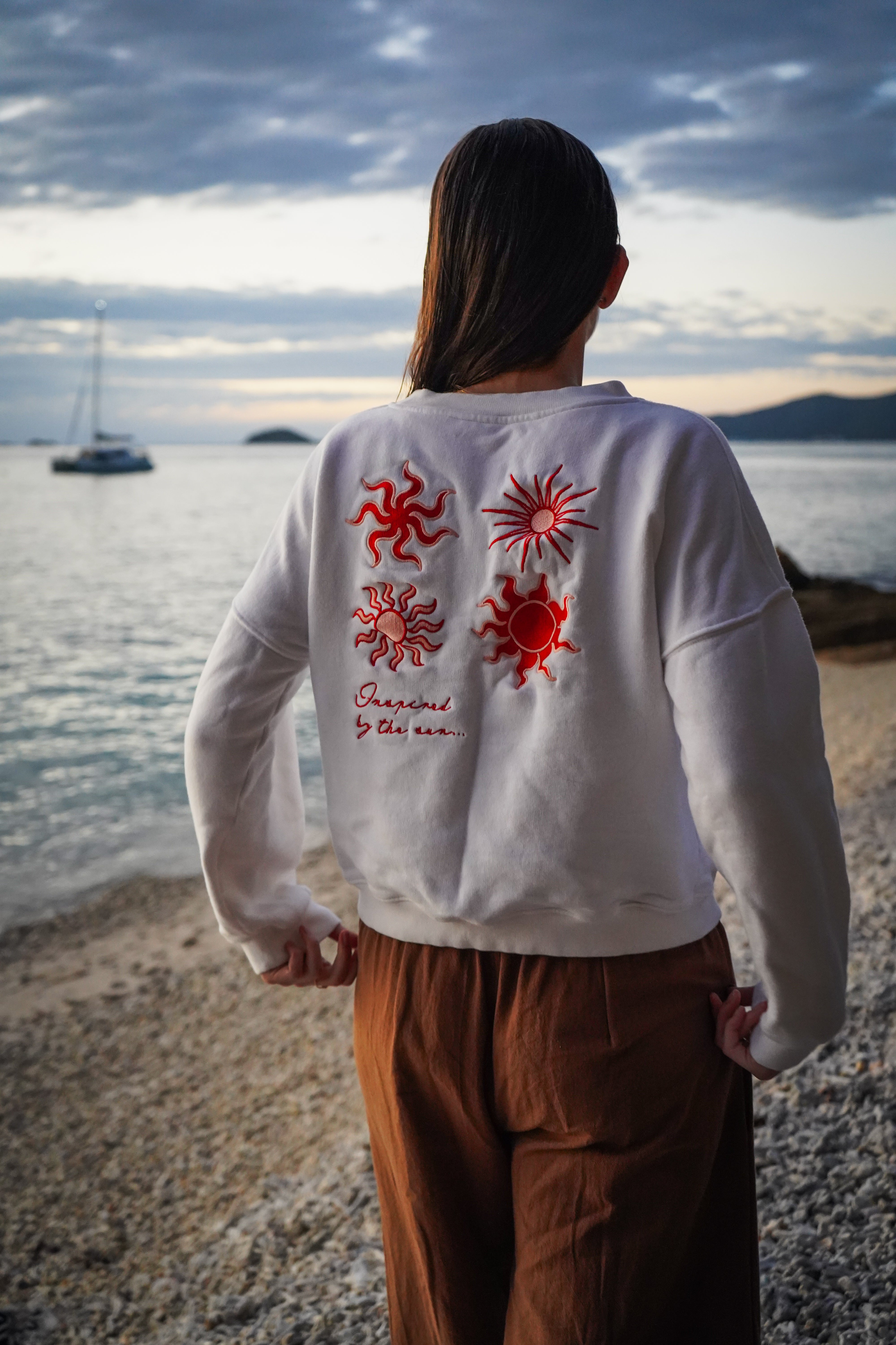 Malia the label, white jumper with red and pink sun embroidery on back. Inspired by the sun collection.