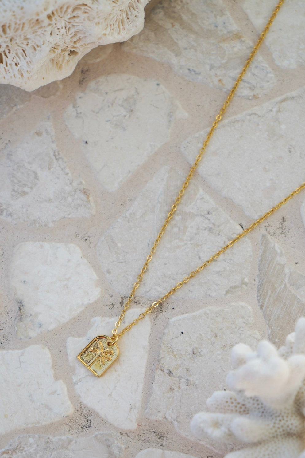 Discover the Isola Gold Necklace, crafted with an etched palm tree pendant on a gleaming gold chain. Lightweight and elegant, it’s the perfect accessory to add a subtle touch of coastal wanderlust to any outfit.