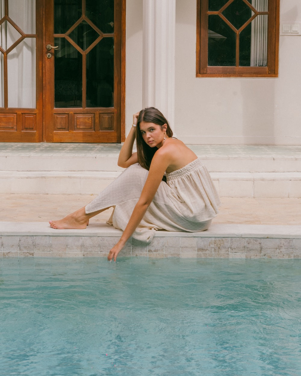 Sorrento Maxi Skirt and Sorrento Strapless top set - model sits by the pool with garment draping along the pool edge - natural fibre clothing brands Australia - Malia the label