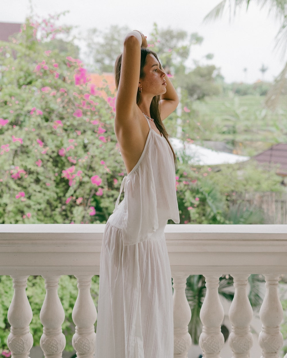 Sole Mare Singlet Top lifestyle shot on villa balcony — side profile showing open backless halter design, model with arm raised against bougainvillea backdrop — 100% handloomed cotton halter top white — Malia The Label La Dolce Vita slow fashion Australia