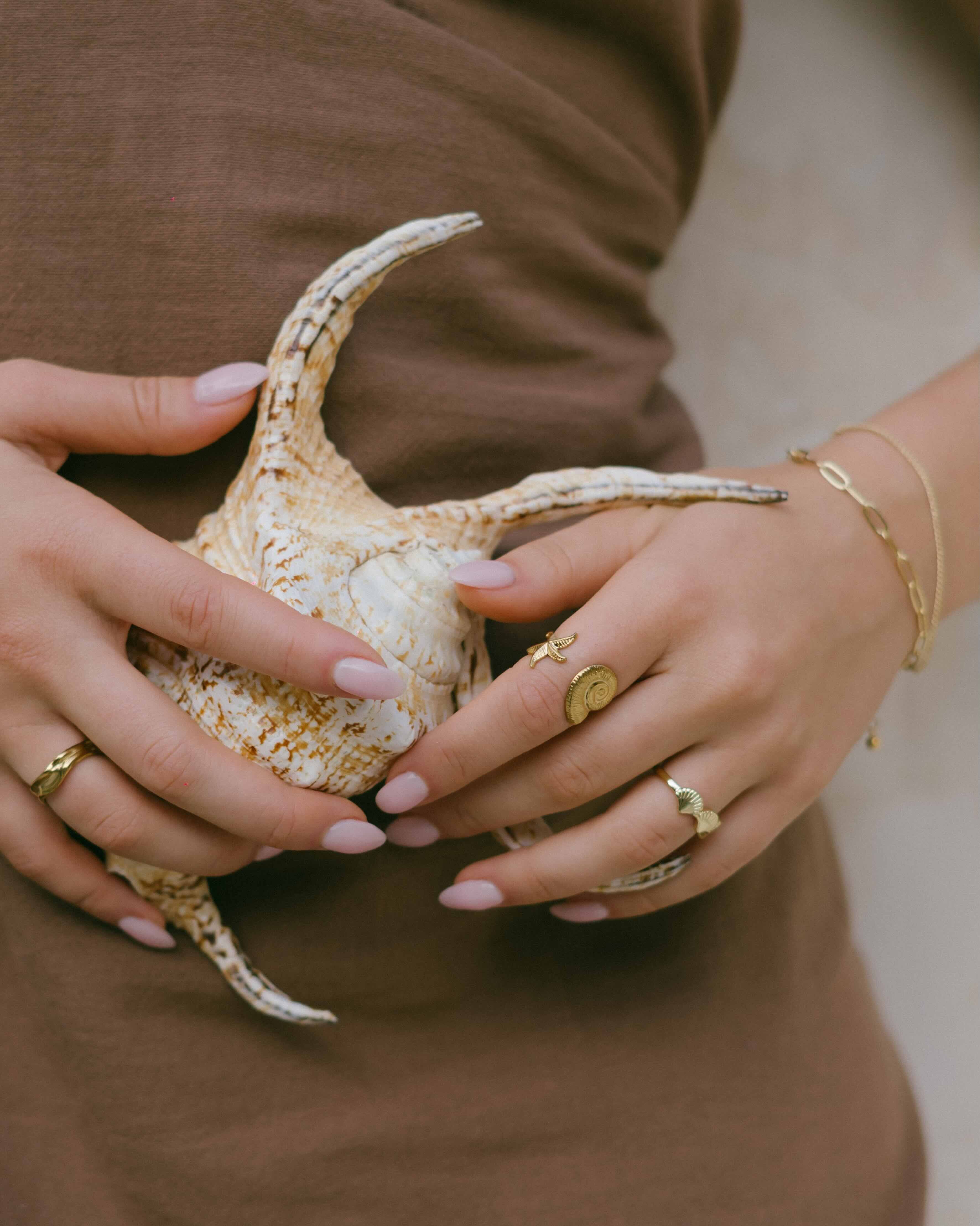 Shop the Tidal Ring—gold open-front ring with a conch shell and starfish design. Adjustable and perfect for ocean lovers.