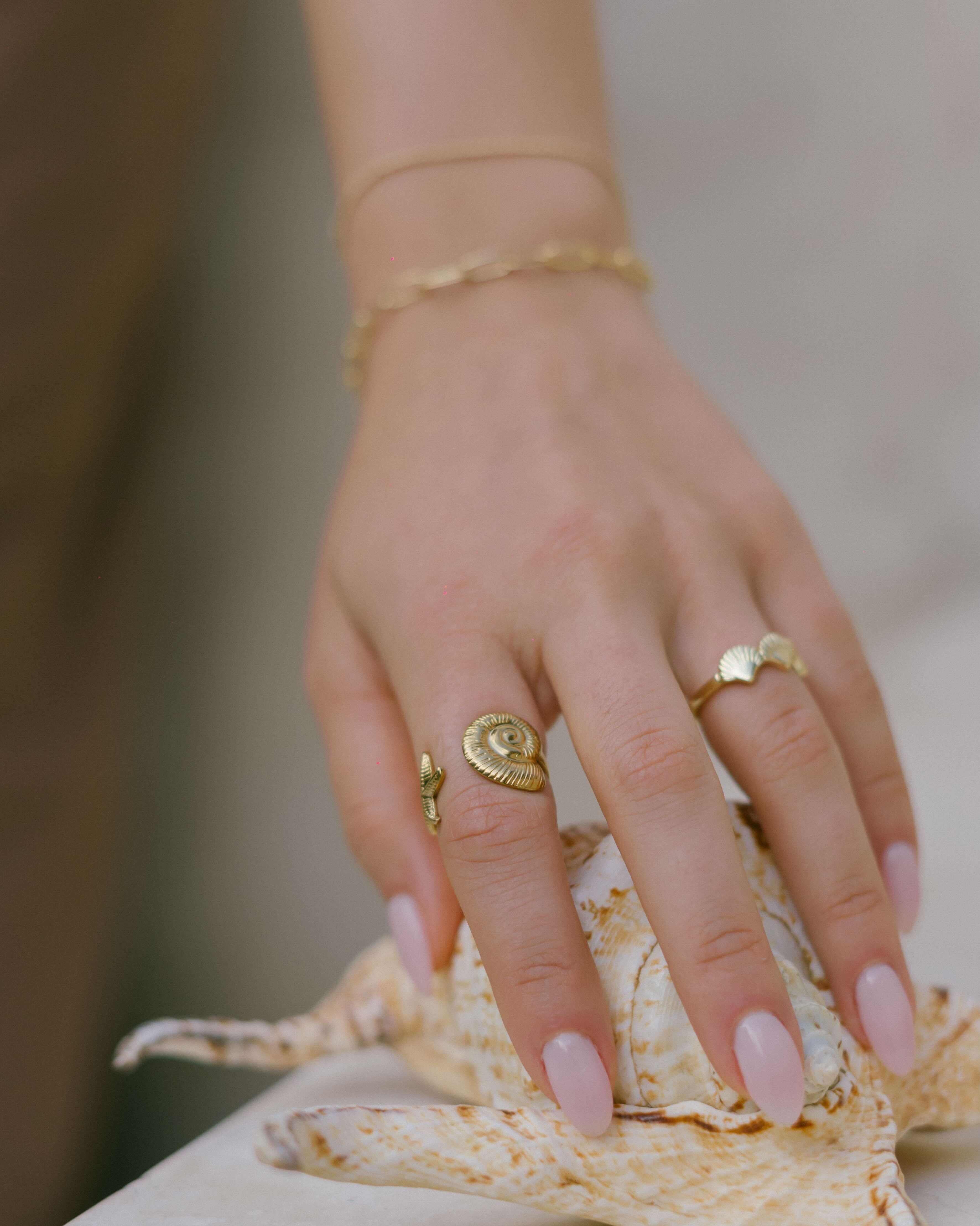 Discover the Tidal Ring—an adjustable gold statement ring inspired by the sea, with a conch shell and starfish detail.