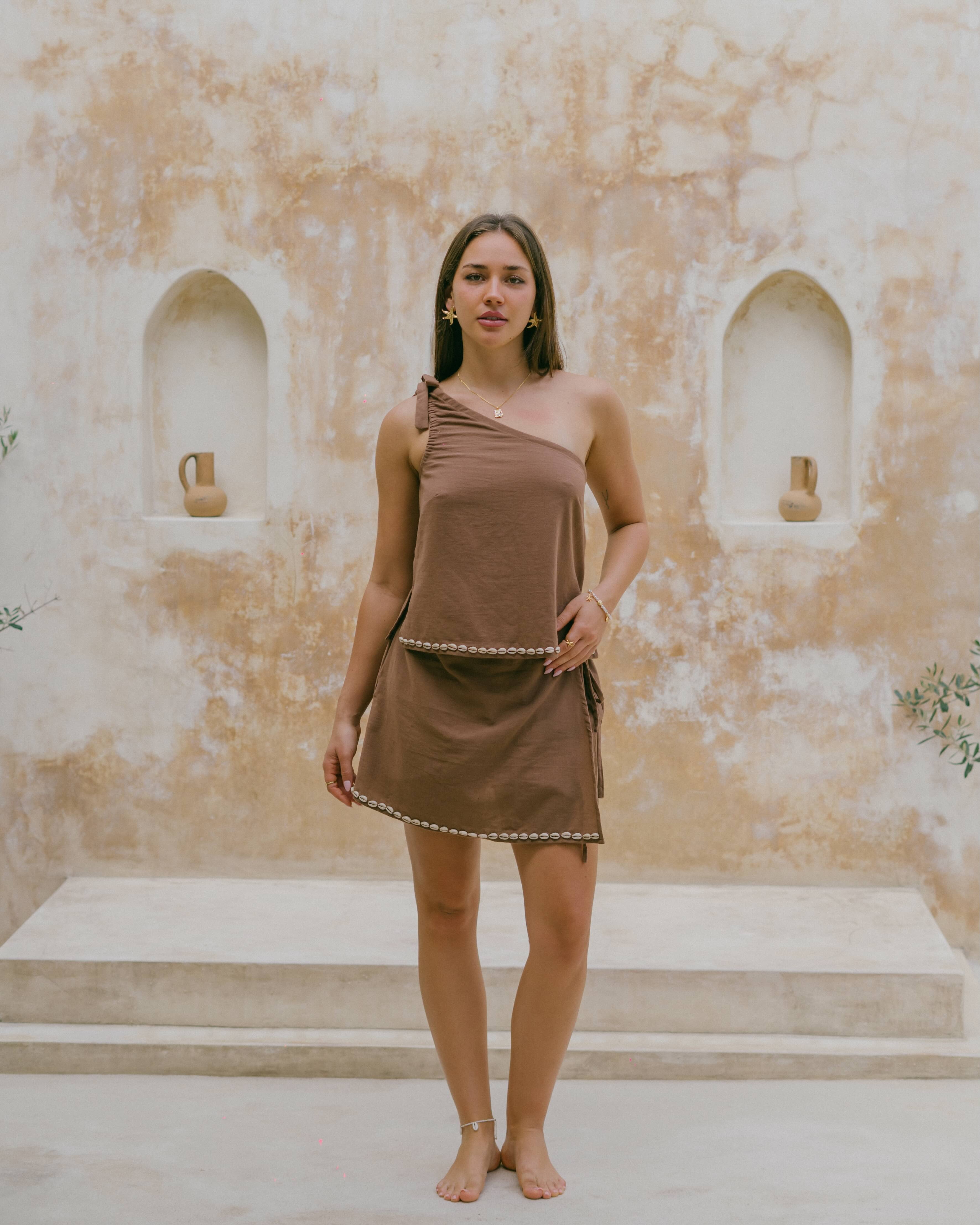 Inspired by the ocean, the Coralie Shell Top offers effortless summer style with a relaxed fit, adjustable tie strap, and chic shell detailing.