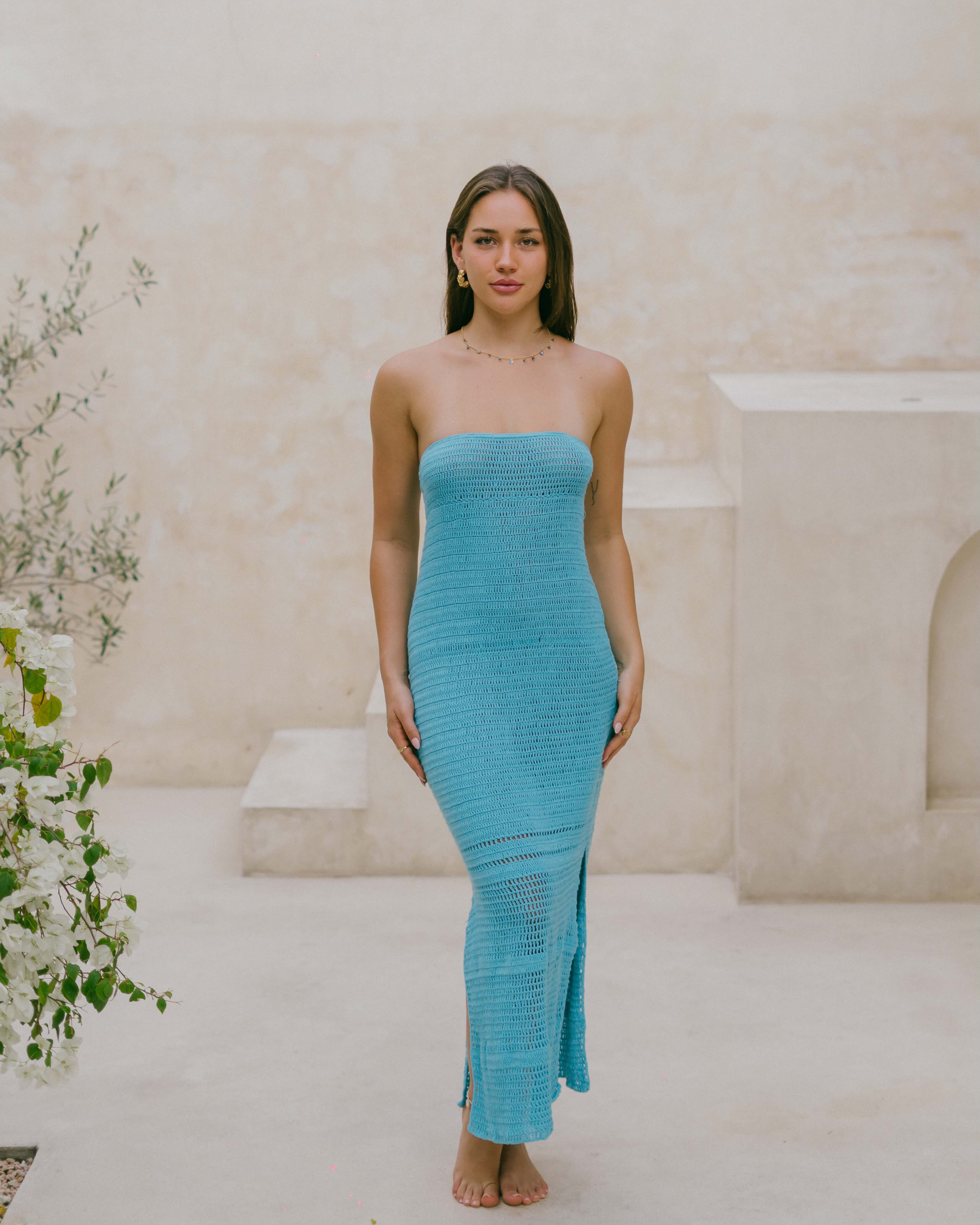 The Azure Crochet Maxi Dress in rich teal blue features a strapless silhouette, open back, and side slits for effortless summer elegance.