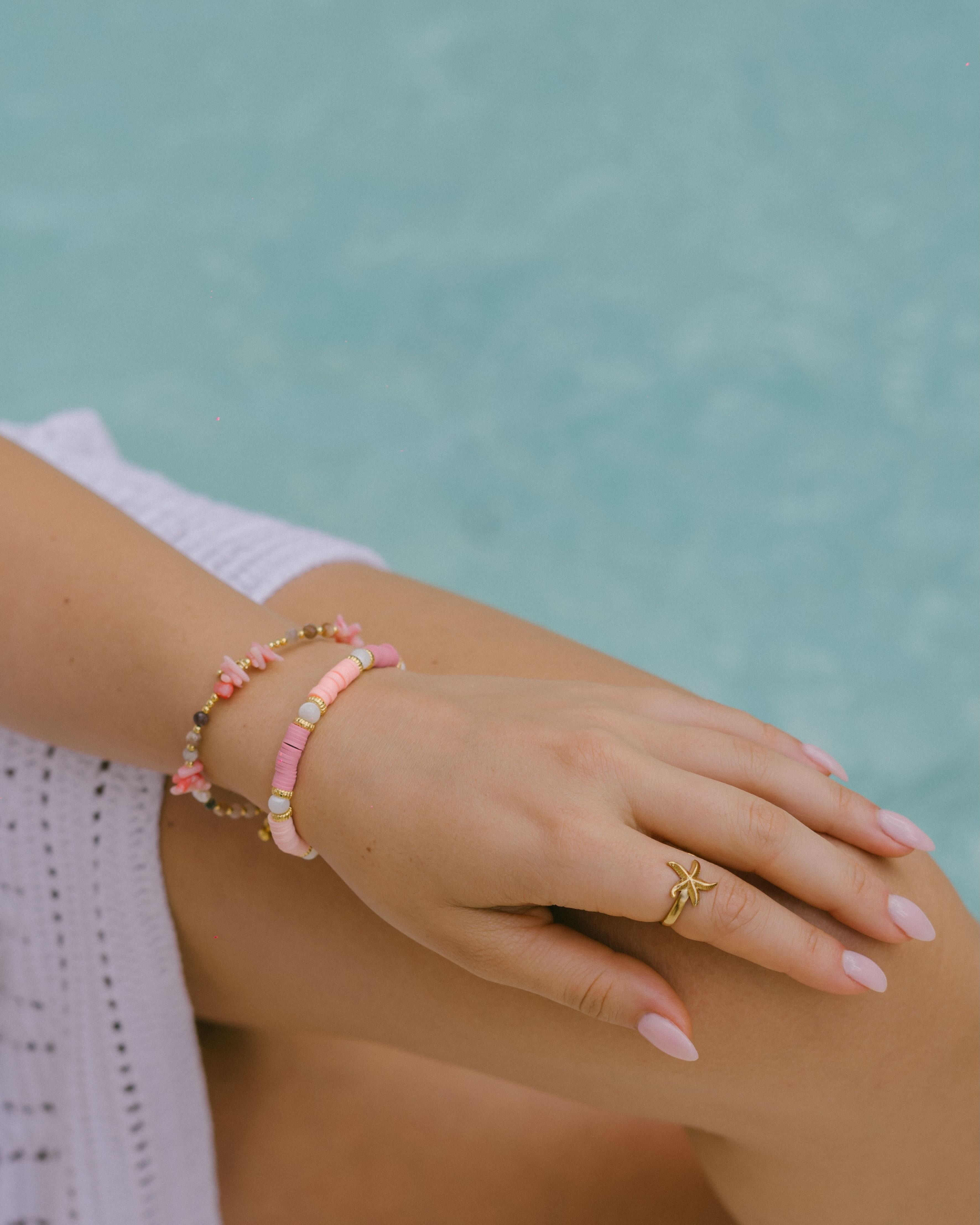 Shop the Coral Rose Bracelet—natural pink stones with gold and crystal beads, accented by three freshwater pearls. A colourful, ocean-inspired accessory.