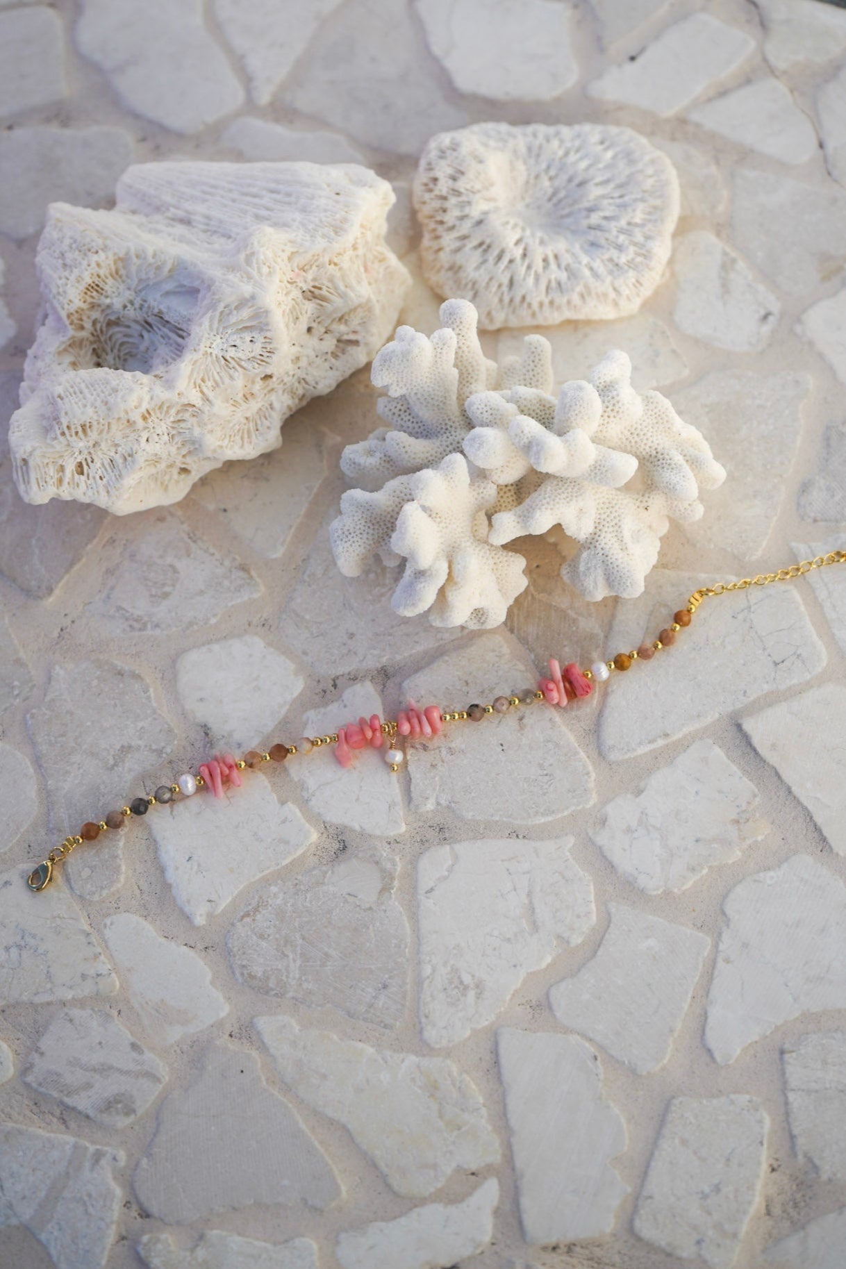 Elevate your style with the Coral Rose Bracelet, featuring pink stone chunks, crystal and gold beads, and freshwater pearl accents for a coastal-chic look.