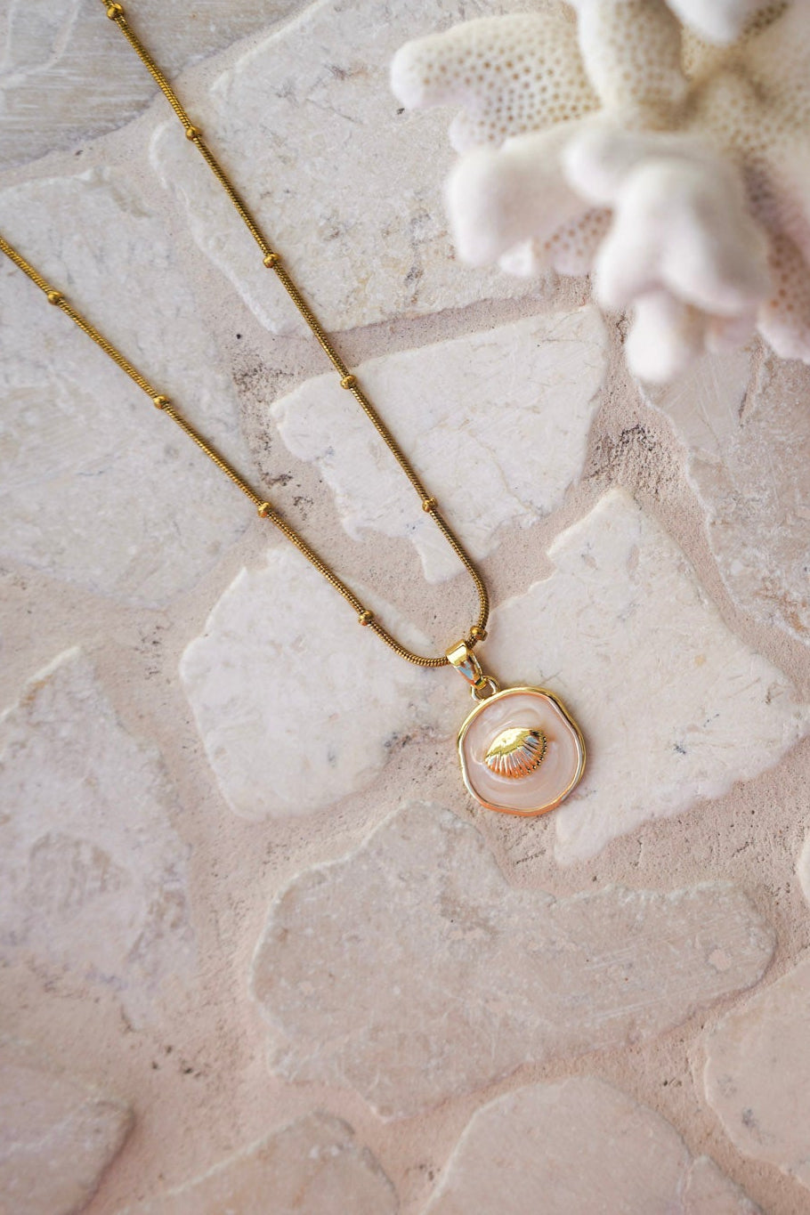 Elevate your look with the Naia Clam Necklace, combining a circle-detailed gold chain with a clam shell pendant on a glossy shell-inspired disc. Durable, waterproof, and ideal for beach lovers.