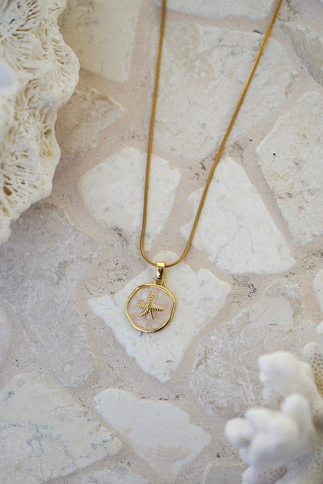 Experience coastal elegance with the Soraya Starfish Necklace—an 18k gold plated stainless steel waterproof necklace featuring a glossy shell circle pendant accented by a delicate starfish charm. Perfect for everyday wear and effortless layering.