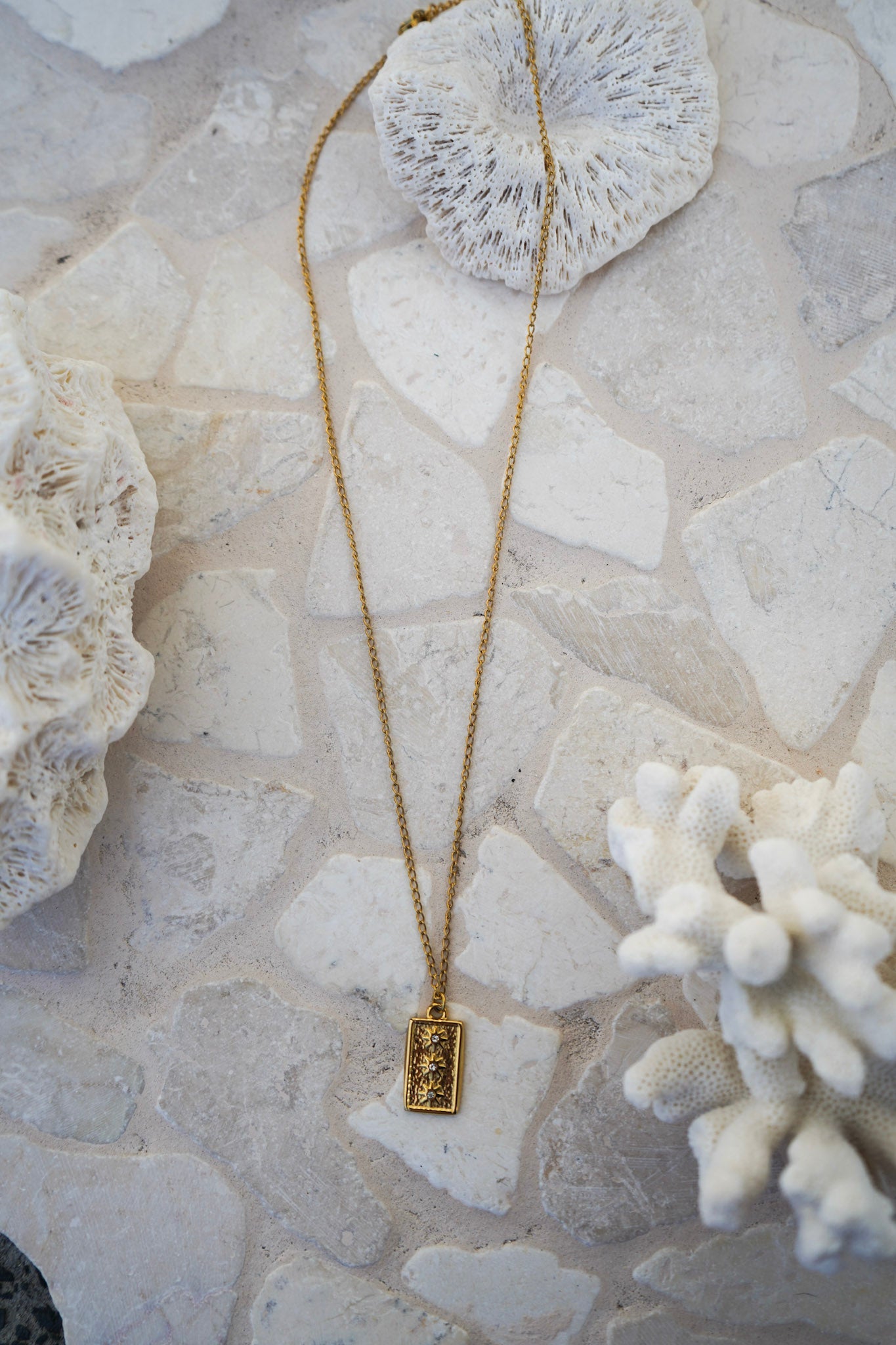 Discover the Junie Necklace, featuring a vertical pendant with three sun motifs and gemstones on an 18k gold plated chain. A celestial-inspired, waterproof necklace perfect for any occasion.