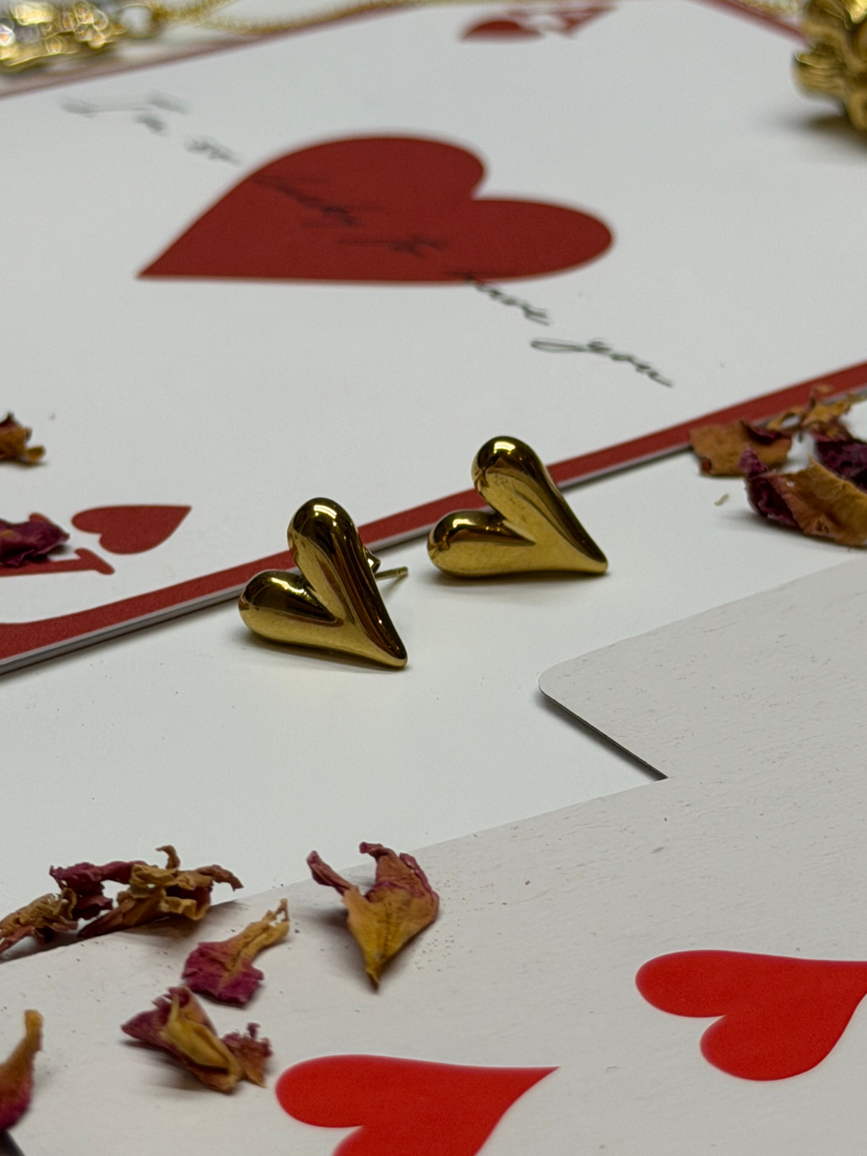 Gold heart-shaped earrings on playing cards with red hearts