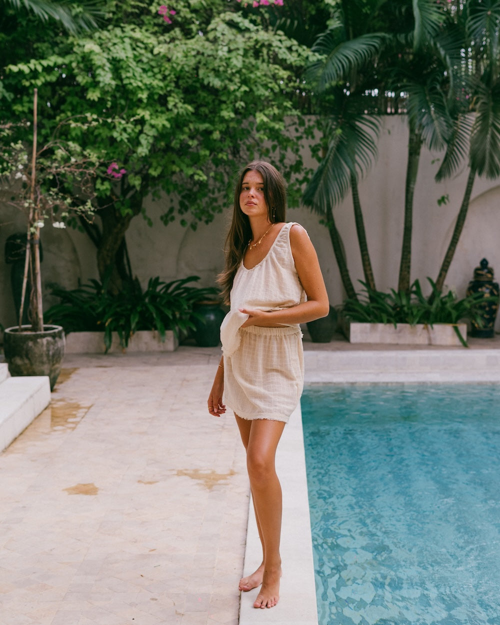 Sofia Singlet and Mini Skirt set in natural check ramie — model standing barefoot at pool edge, full-length view showing matching co-ord set with frayed hems — natural ramie cotton matching set — Malia The Label La Dolce Vita — slow fashion Australia