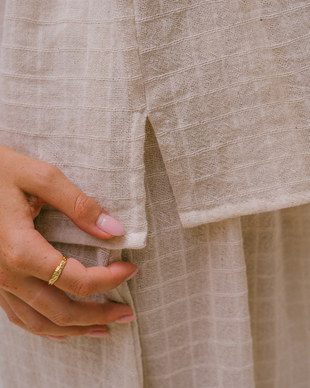 Sorrento Strapless Top and Maxi Skirt fabric and split detail close-up — hand showing side split on gathered strapless top hem above maxi skirt waistband, textured check ramie weave in natural cream — natural fibre ramie texture and split detail — Malia The Label La Dolce Vita collection